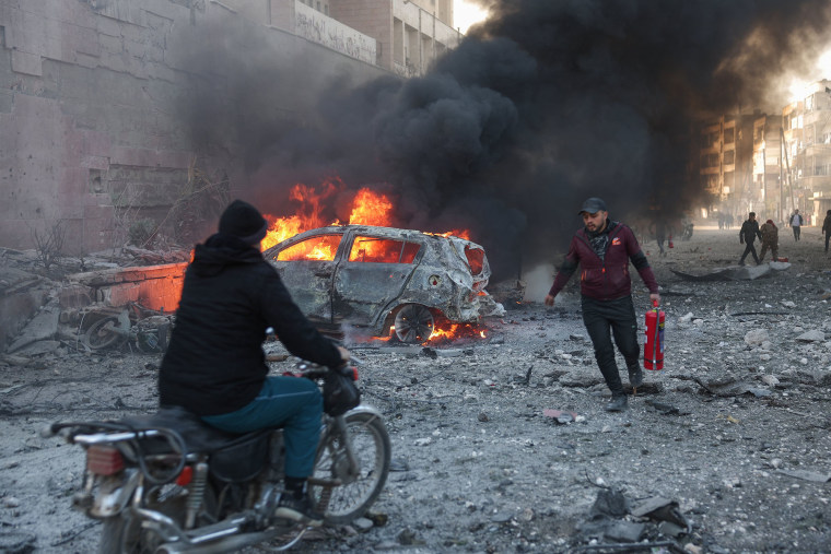 People try to extinguish fires following an airstrike that targeted Syria's rebel-held northern city of Idlib on Dec. 2, 2024.