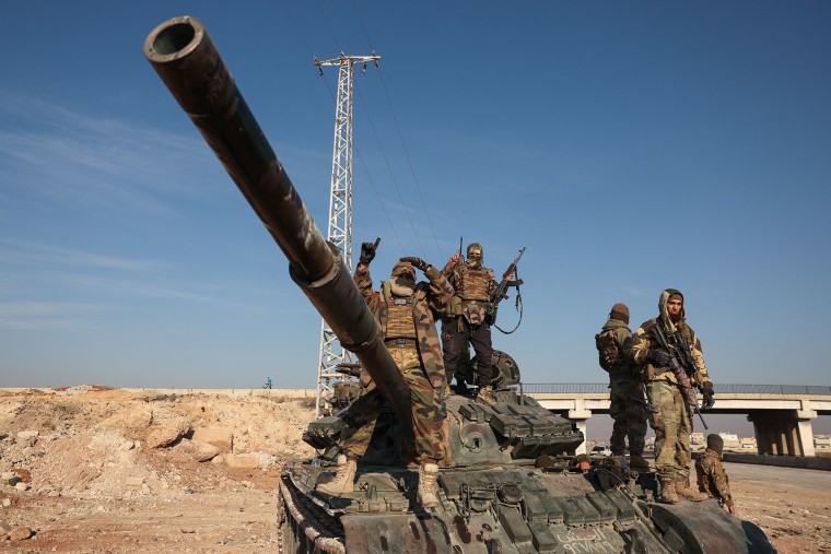 Anti-government fighters stand on abandoned Syrian army vehicles