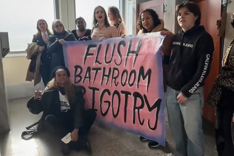 People hold a sign saying "Flush Bathroom Bigotry"