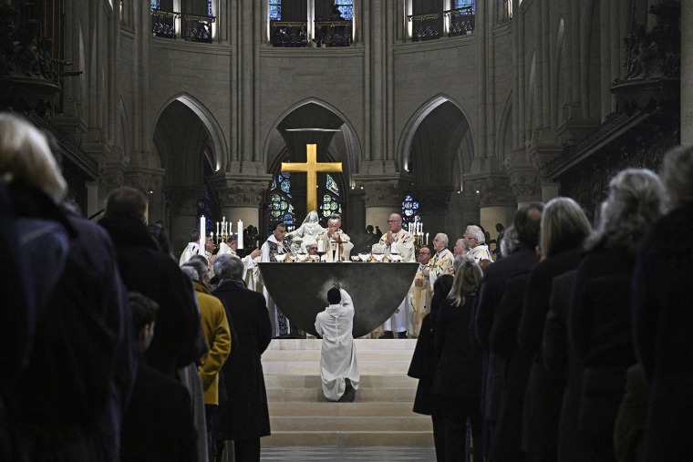 A member of the clergy kneels down as the Archbishop of Paris Laurent Ulrich leads prayers for the consecration of the new main altar at the Notre Dame cathedral 