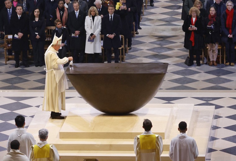 The Archbishop of Paris Laurent Ulrich anoints the new main altar as France's President Emmanuel Macron and first lady Brigitte Macron look on 