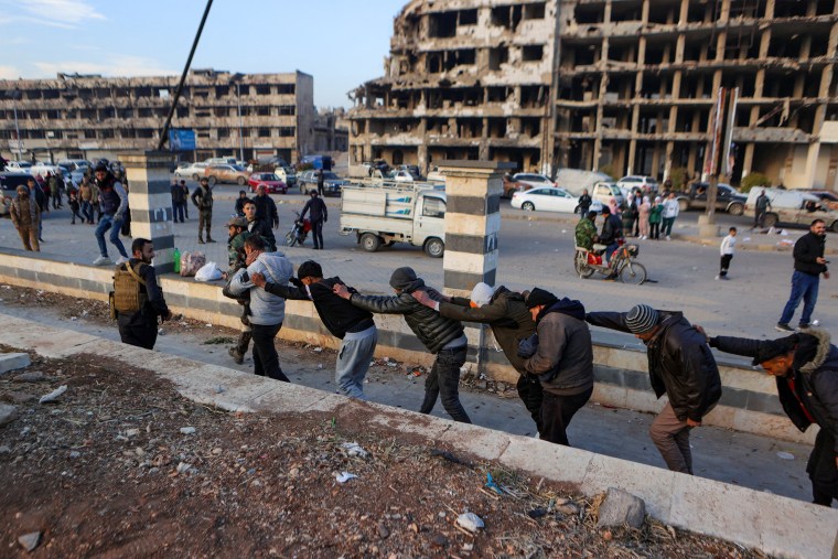 Syrian rebel fighters parade detained members of the Syrian government's forces in civilian clothing in Homs