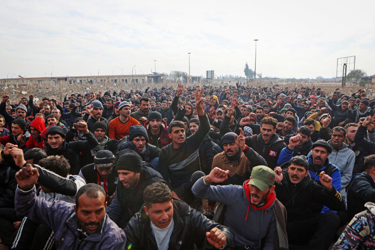 Detained members of the Syrian government security forces are gathered outdoors at a makeshift detention facility 