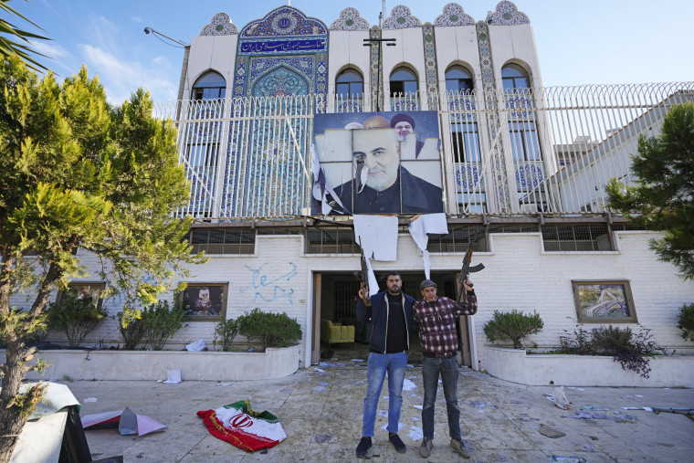 Syrian opposition fighters stand at the entrance to the ransacked Iranian embassy in Damascus on Dec. 8, 2024. 