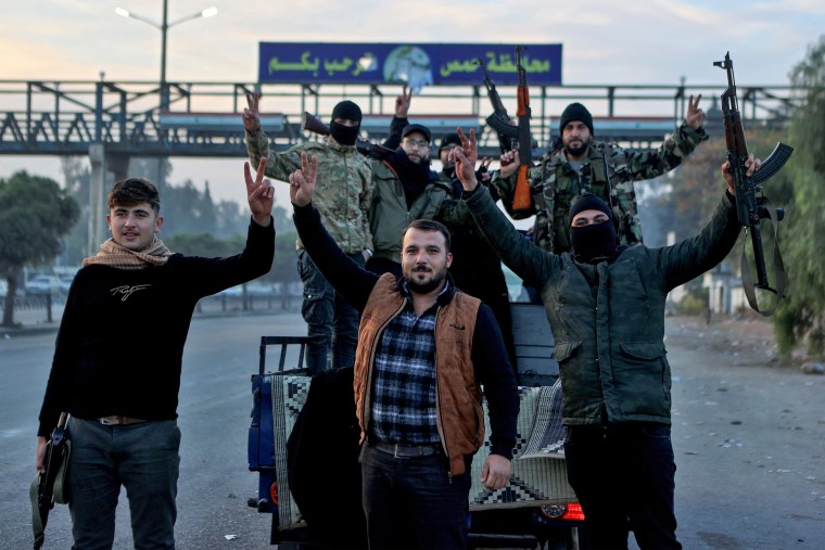 Syrian rebel fighters celebrate at the entrance of Homs province 