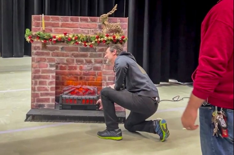 A person next to a prop fireplace.