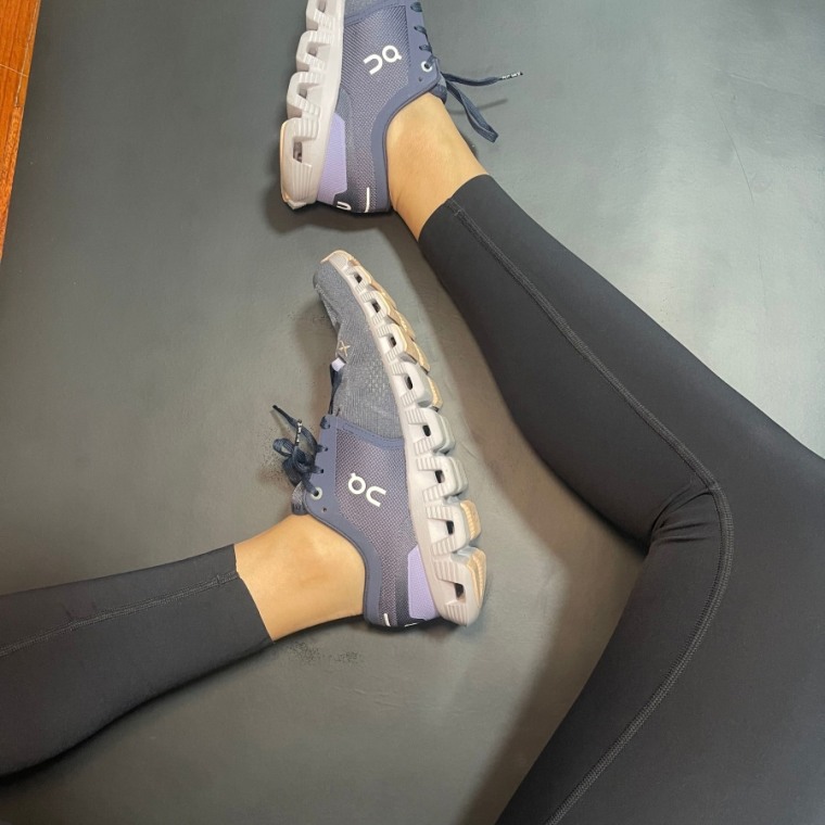 Woman sits criss-cross in her black Lululemon Base Pace High Rise Tight leggings and highlights the unhemmed bottom.