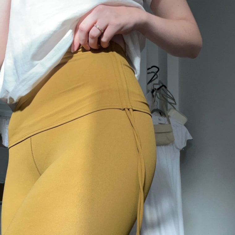 Woman wears a mustard yellow pair of the Neiwai Active Ballet Stirrup Drawstring Leggings.