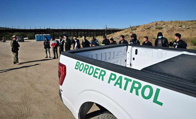 A large group of Chinese migrants, including three from Bangladesh, line up for a Customs and Border Patrol officer