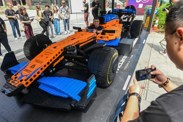 La gente fotografía el auto de carreras de Fórmula 1 LEGO Technic McLaren de tamaño natural en Singapur el 23 de septiembre de 2022.