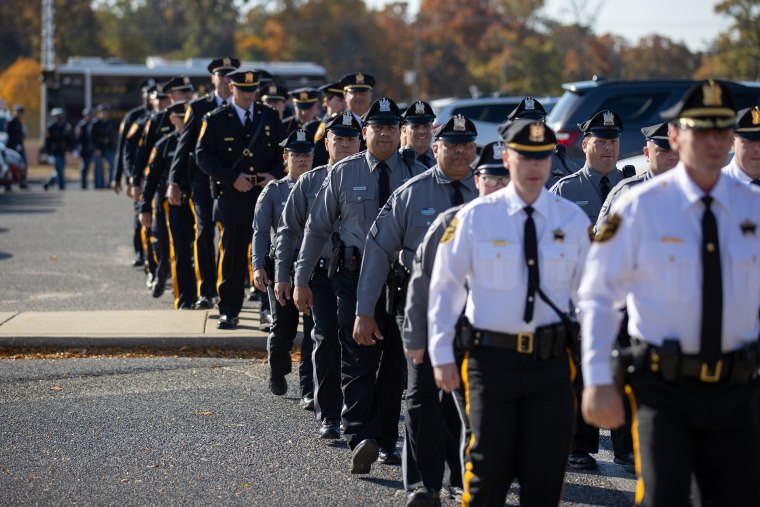 Police officers walk in line for the funeral