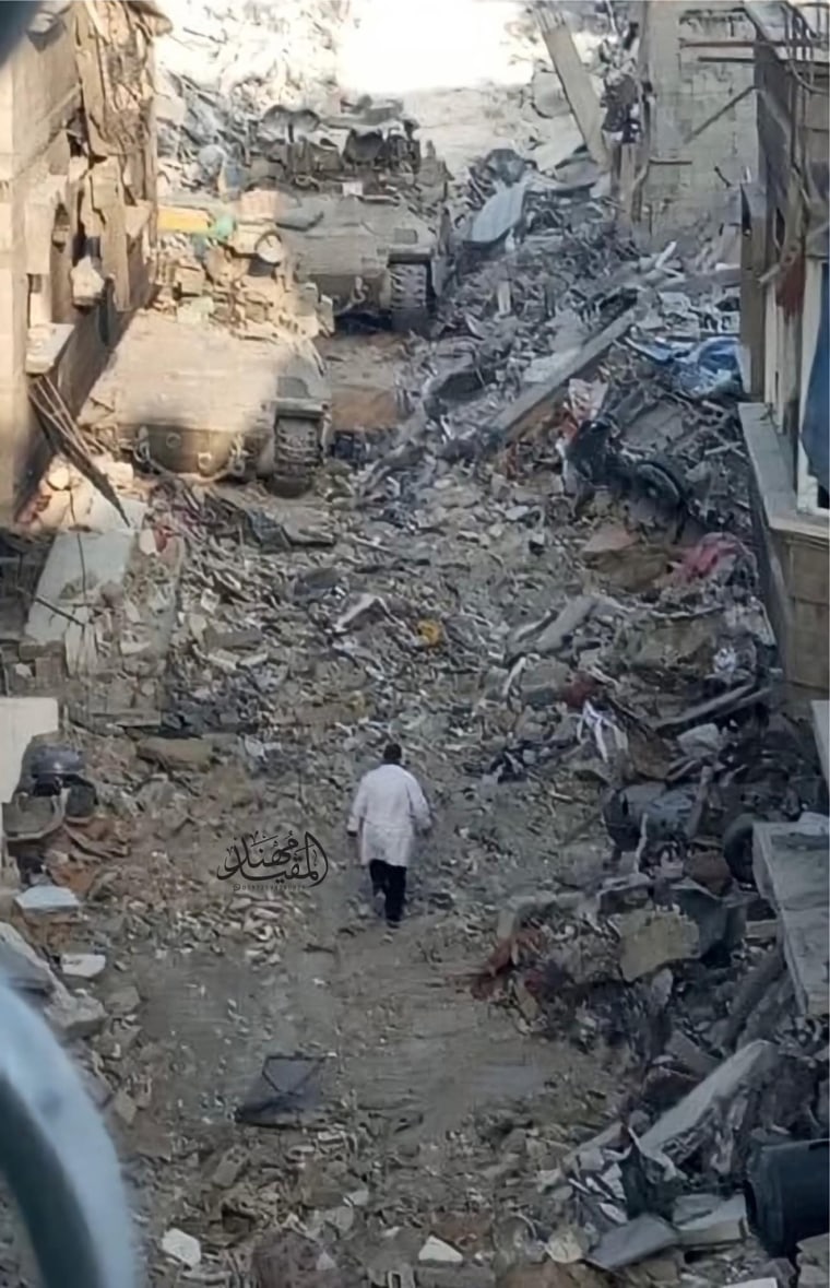 Dr. Hussam Abu Safiya seen walking down a damaged street.