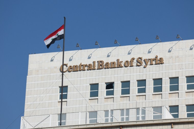 A Syrian flag flutters at Syrian Central Bank