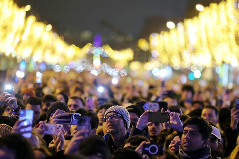 Los juerguistas se esfuerzan por ver cómo miles de personas se reúnen en la Avenida de los Campos Elíseos para dar la bienvenida al Año Nuevo, en el centro de París, el 31 de diciembre de 2024.