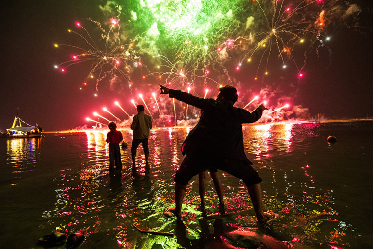 Local residents look at fireworks as they celebrate the New Year at Ancol Beach in Jakarta on January 1, 2025.