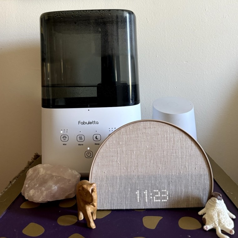 The Fabuletta humidifier on a table behind a crystal, a Hatch Restore 2 clock and decorative figurines.