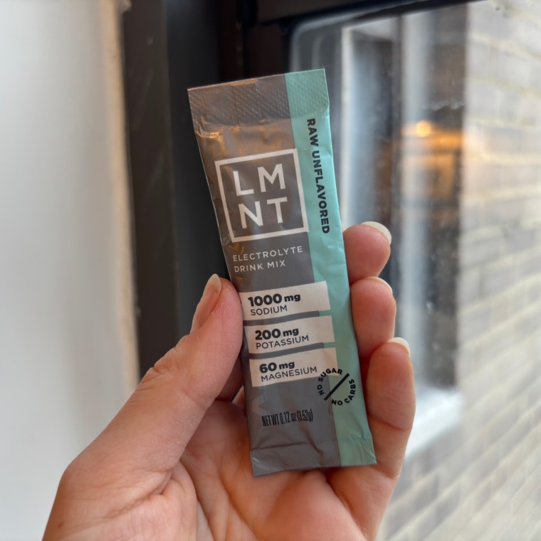 A hand holding a single-serve packet of LMNT electrolyte powder.