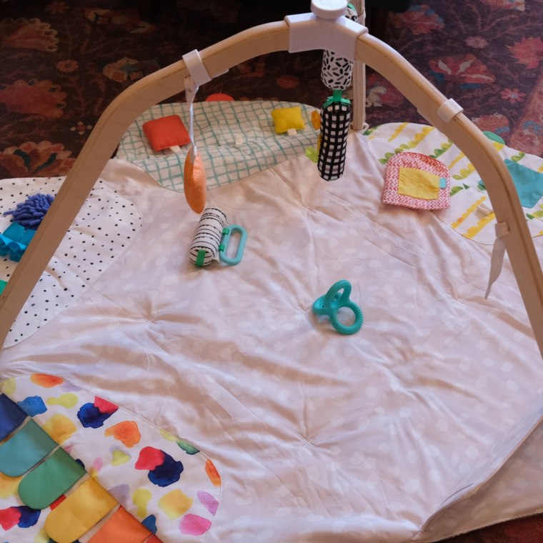 A close-up of the Lovevery Play Gym with a few baby toys lying in the center of the play mat.