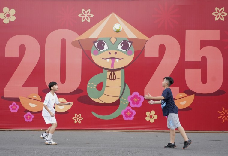 Two boys playing soccer in front of a sign welcoming the new year 2025