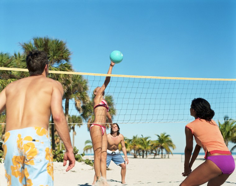 Four people playing volleyball on beach