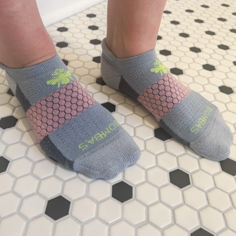 Woman wears a gray Bombas Marl Ankle Sock pair without shoes on.