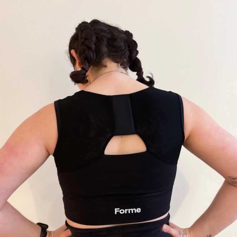 A profile view of a woman wearing a black shirt with the Forme Power Bra (left) and the Brooks Scoopback Sports Bra (right).