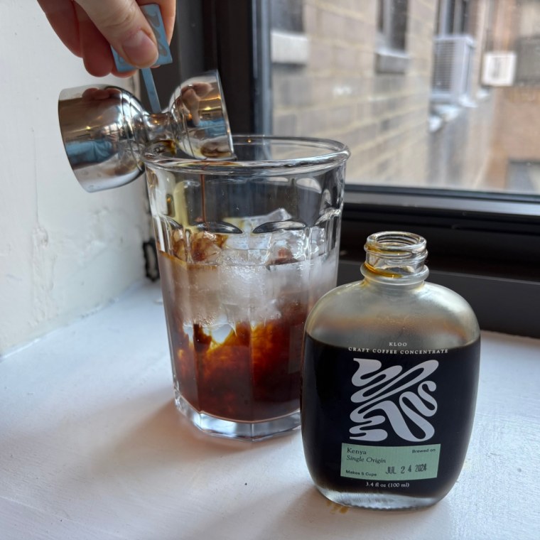 Woman pouring coffee into glass cup with Kloo coffee concentrate bottle on the side