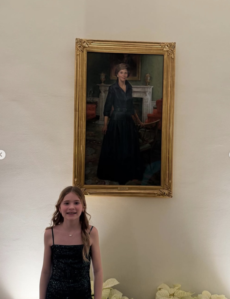 Mila stands in front of a picture of former first lady Laura Bush