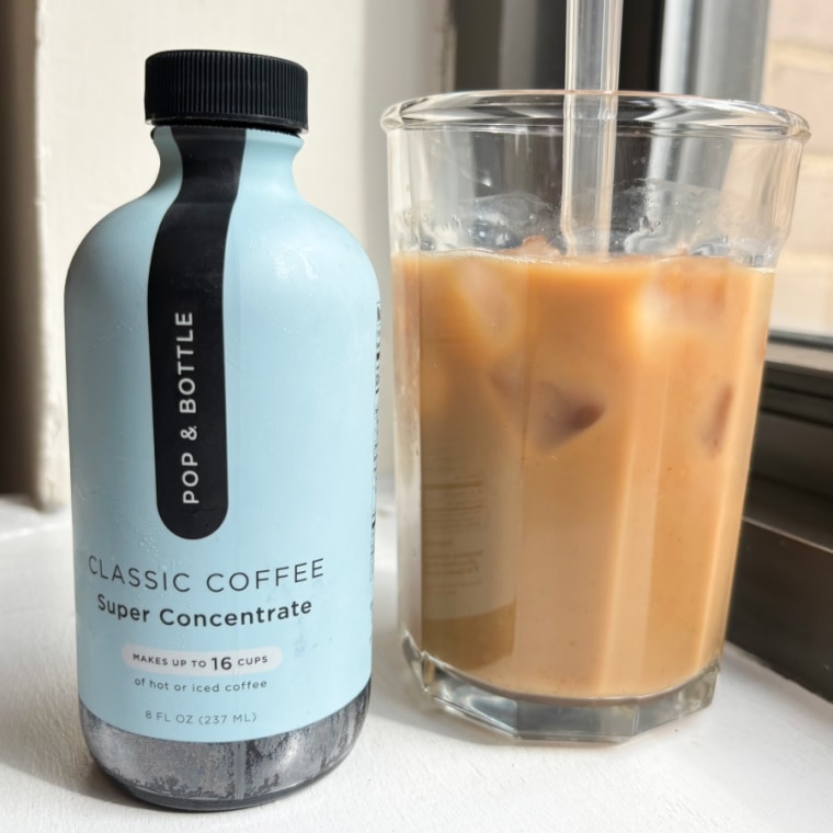 Bottle of Pop & Bottle coffee concentrate next to a glass cup of coffee with straw