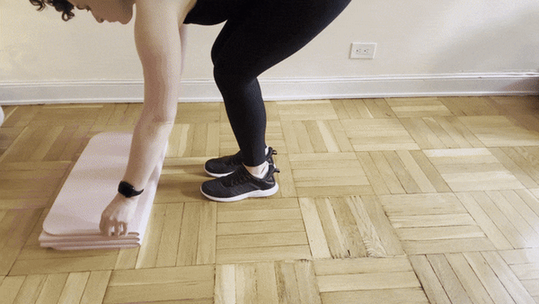 A woman folding in a panel of a pink Stakt Mat and placing her knees on top of it.