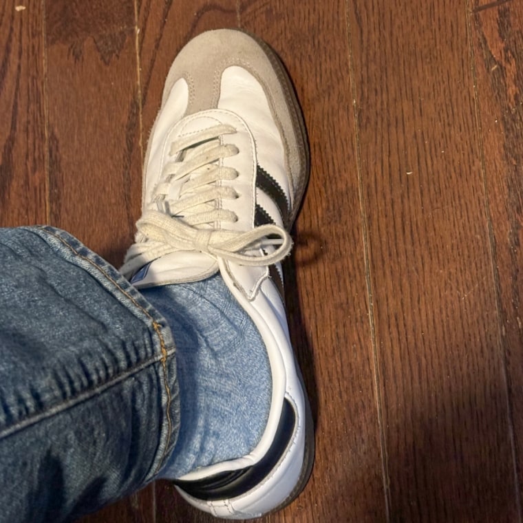 Close-up shot of someone’s ankle waring the  light blue crew sock and Adidas Sambas sneakers.