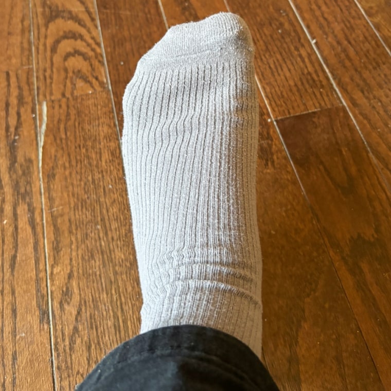 Writer’s foot in  Uniqlo’s gray crew sock on wooden floor.