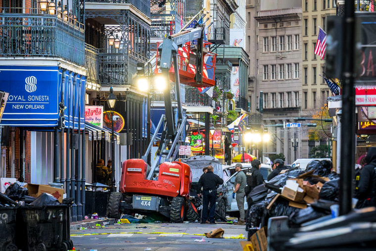 Image: Police investigators surround a white truck that has been crashed into a work lift