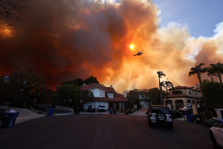 Plumes of smoke are seen as a brush fire burns near homes outside