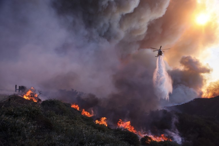 Water is dropped by helicopter on the advancing Palisades Fire