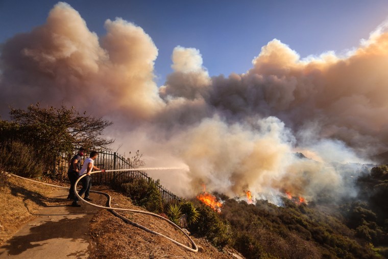  A resident attempts to protect his property from the flames closing in