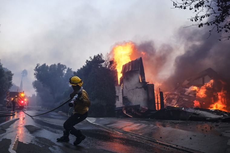 A firefighter battles the advancing Palisades Fire