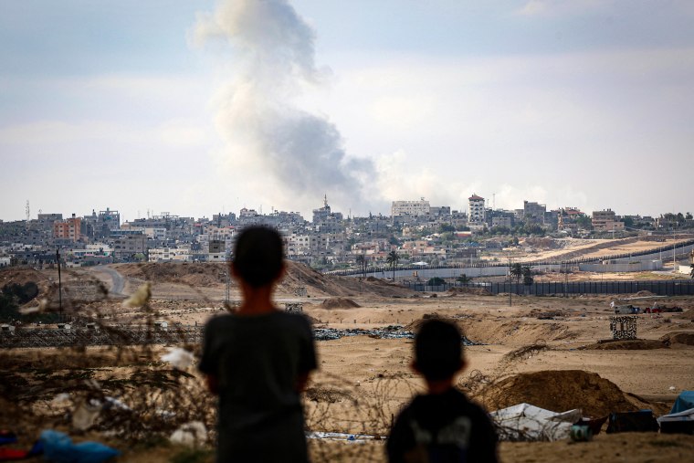 Young boys look astatine billowing fume against a metropolis skyline.