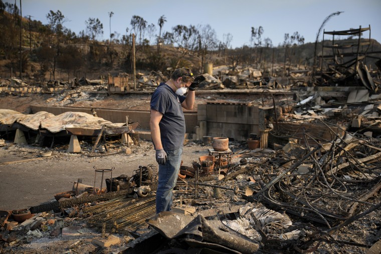 Kevin Marshall sifts through his mother's fire-ravaged property in the the Palisades Fire in the Pacific Palisades neighborhood on Saturday.