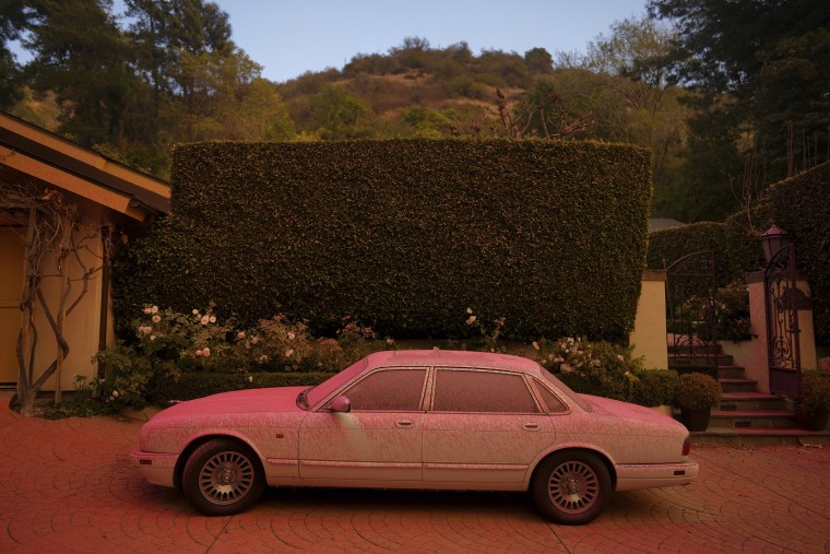 A vehicle is covered in fire retardant while crews battle the Palisades Fire in Mandeville Canyon on Saturday in Los Angeles. 