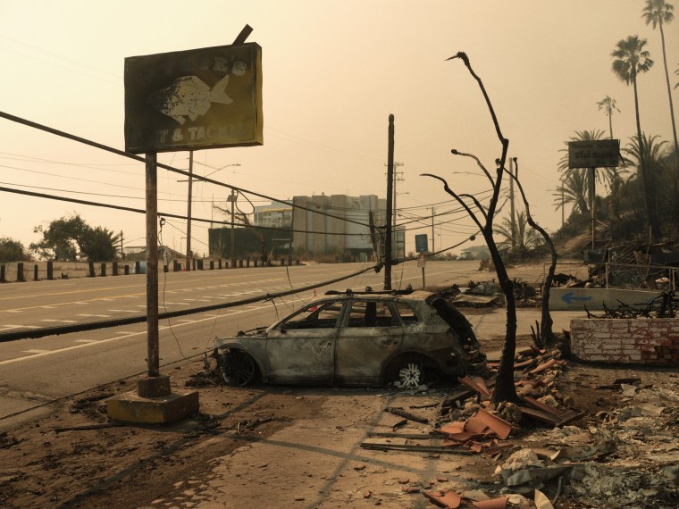 A charred sign for Wylie's Bait and Tackle and a burned out car.