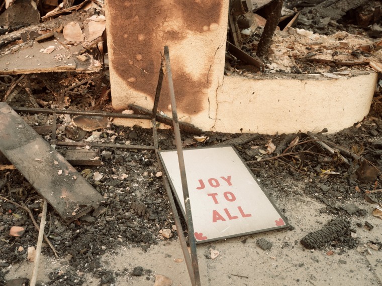 A sign reads "Joy to All" amongst rubble on the ground.