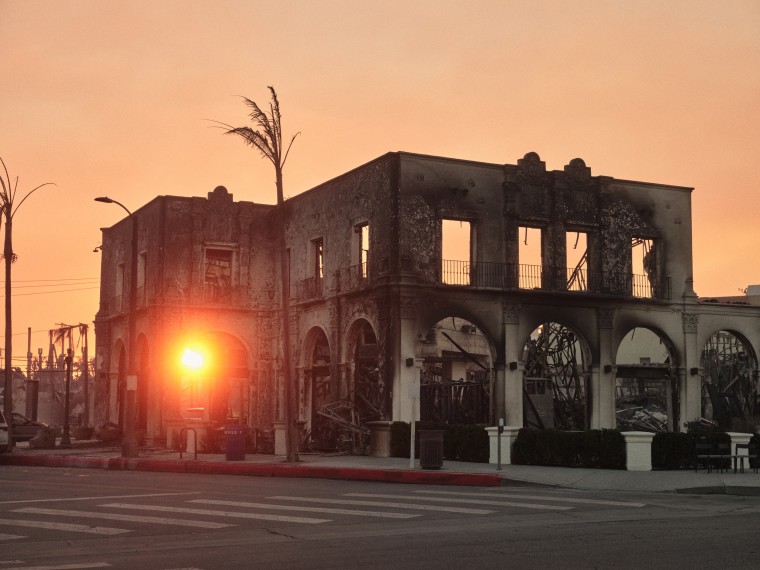 A sunset through a charred and destroyed building.