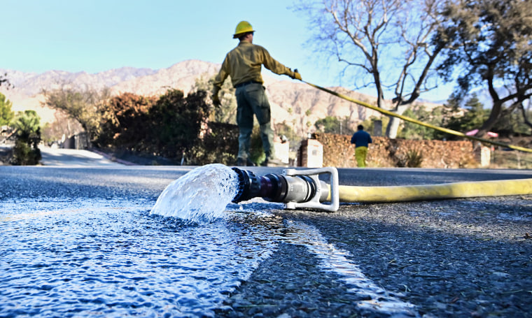 Water flows out of a hose as firefighters water down smoky embers on Jan. 13, 2025 in Altadena, Calif.