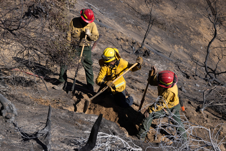 Firefighters combatting the Eaton Fire clear a hot spot above Altadena on Jan. 14, 2025.