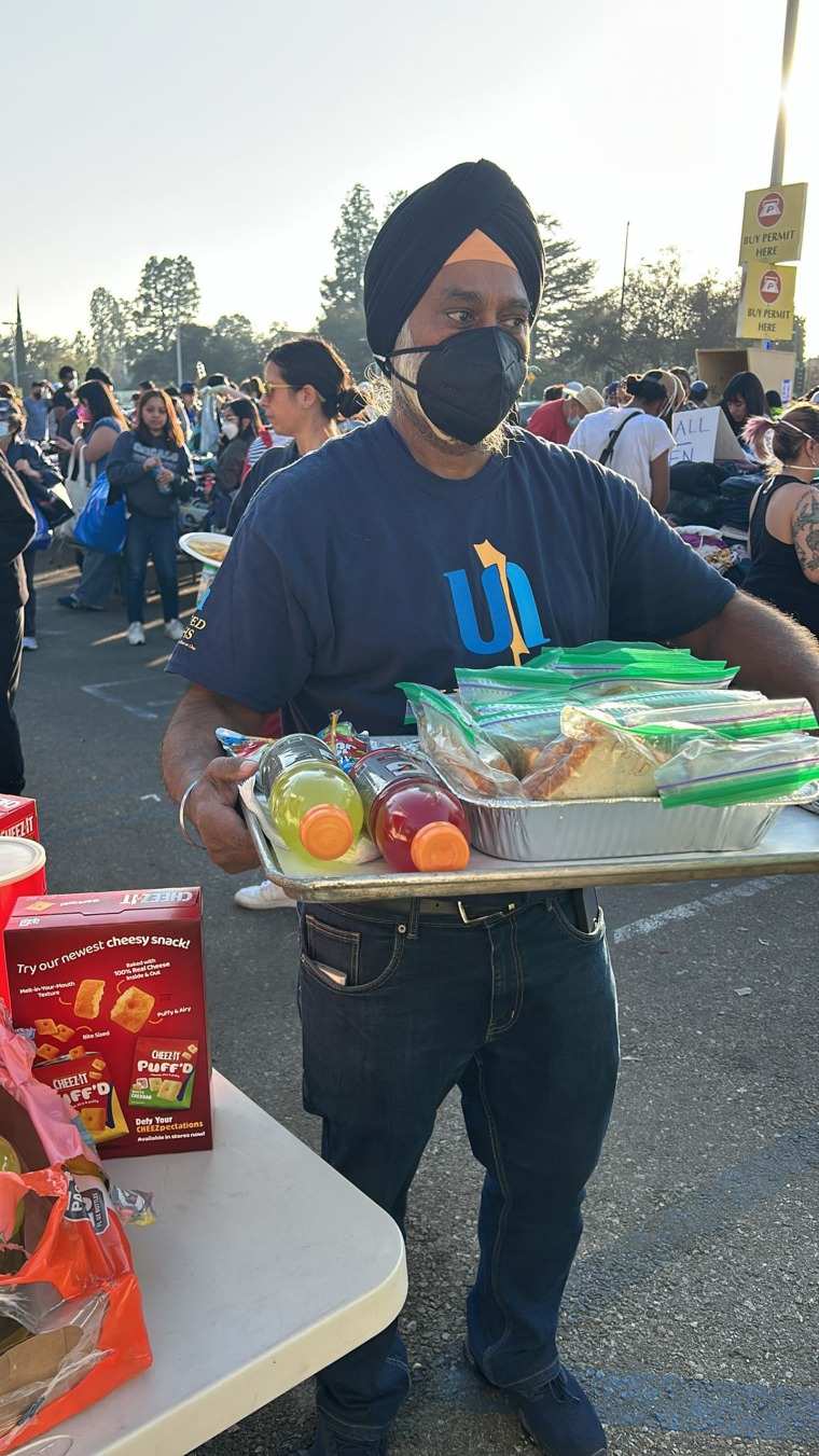 A man wearing a mask and headband holds a tray of sandwiches and gatorade