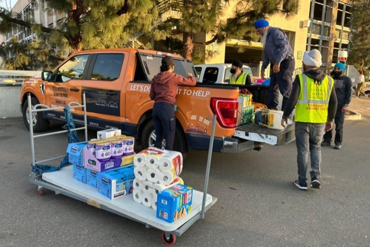 People load paper towels, formula and other items into a truck bed outdoors