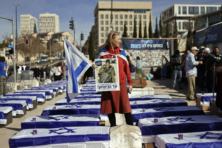 A demonstrator stands amid mock coffins draped in Israeli flags to protest the ceasefire with Hamas outside the Supreme Court in Jerusalem on Jan. 16, 2025. 