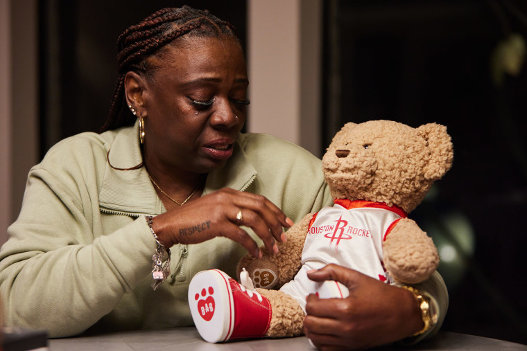 Janice Hughes holds a stuffed teddy bear while talking about her son. The bear plays a recording of Ashtian’s voice when squeezed.