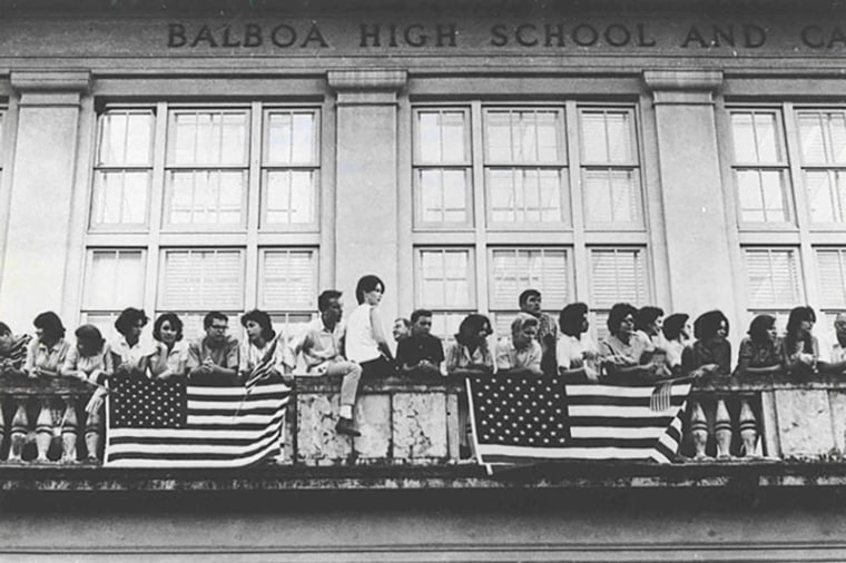 American students in the US Controlled Canal Zone on the balcony of Balboa High School displaying the American flag on January 9, 1964.